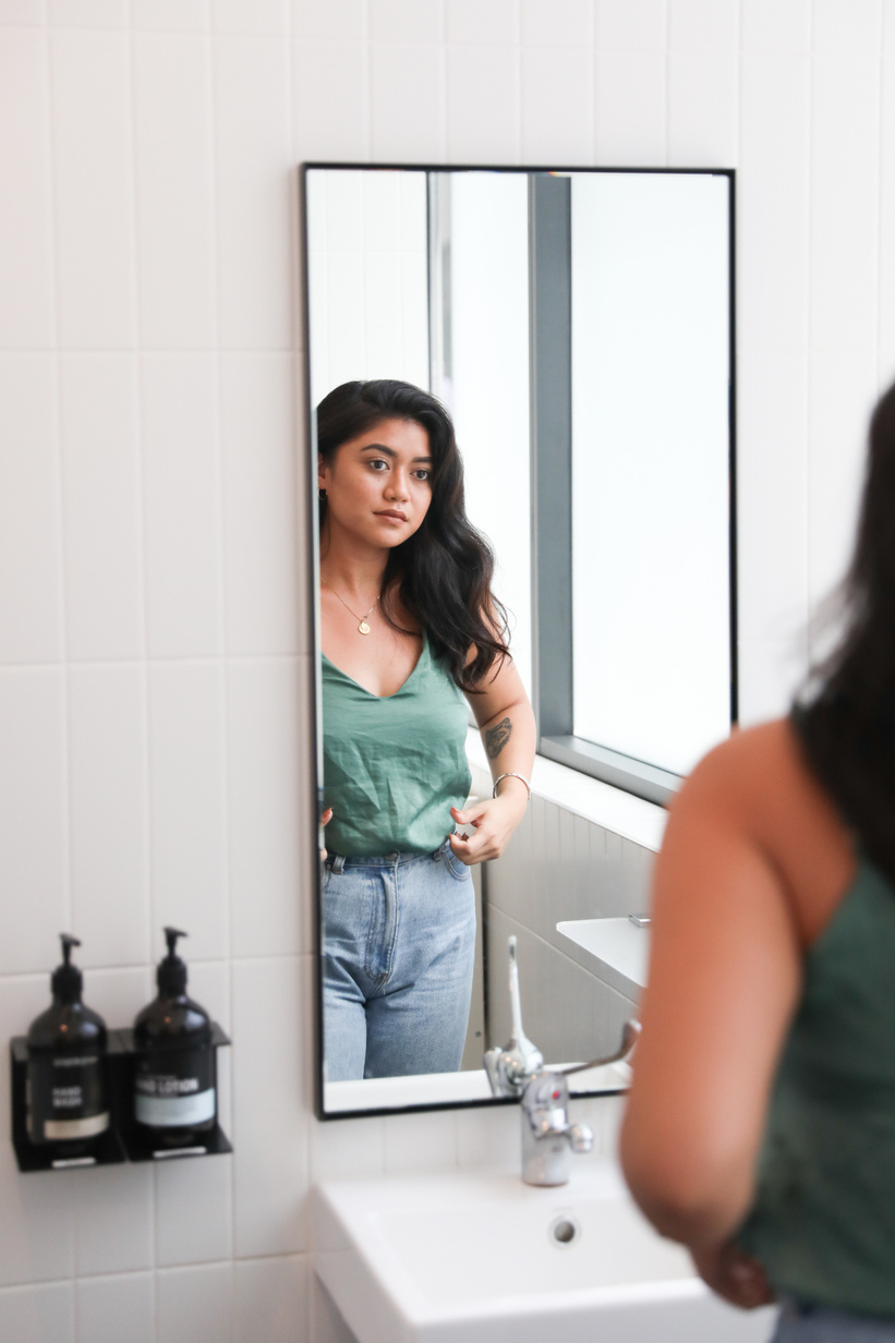 Woman looking at self in mirror in office toilet